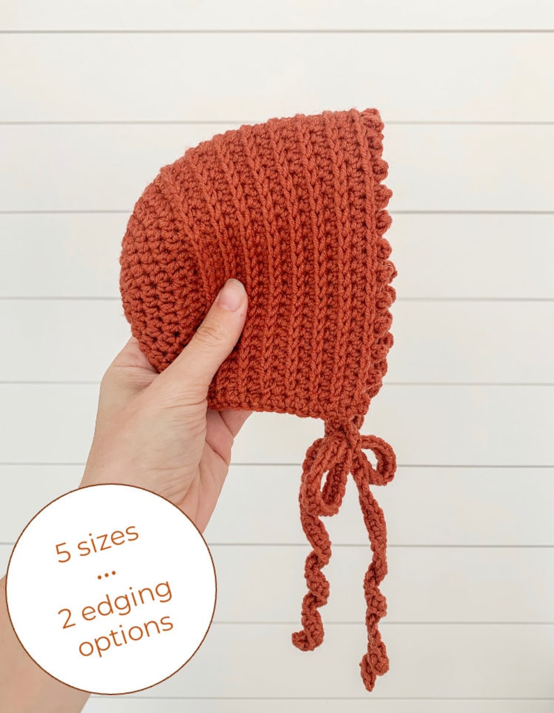 May include: A crocheted baby bonnet in a burnt orange color with a scalloped edge and a tied bow. The bonnet is available in 5 sizes and 2 edging options.