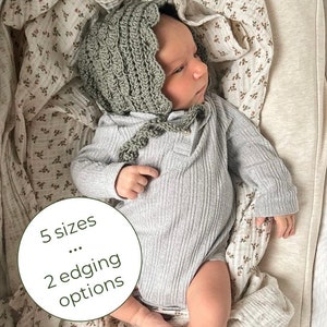 Op de afbeelding: Een baby draagt een saliegroene gehaakte muts met een gegolfde rand, een grijze geribbelde romper en een witte mousseline-wikkel met een bruine bloemenprint. De tekst "5 maten... 2 zoomopties" is zichtbaar in de afbeelding.