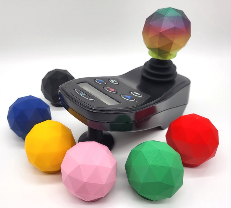 May include: A black joystick with a rainbow-coloured ball on top and six buttons. There are six colourful, geometric balls surrounding the joystick.