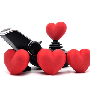 May include: A black joystick with four red heart-shaped buttons. The joystick is made of plastic and metal. The hearts are made of a soft, fuzzy material.