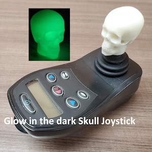 May include: A black joystick with a white glow-in-the-dark skull on top. The joystick has a digital display and several buttons.