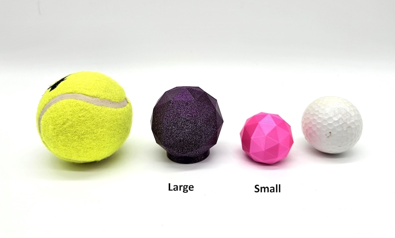 May include: Four different sized balls, a yellow tennis ball, a large purple ball, a small pink ball, and a white golf ball.