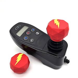 May include: A black joystick controller with a red and yellow lightning bolt design on the top. The controller has a digital display and several buttons.