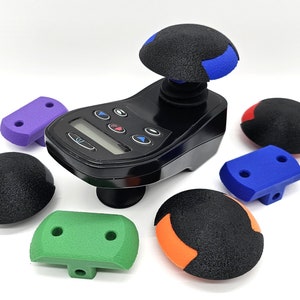 May include: A black massage device with a digital display and multiple attachments. The attachments are different colours, including blue, green, orange, and purple.