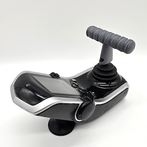 May include: A black and silver remote control with a textured grey handle. The remote has a screen and buttons. It is mounted on a black base.