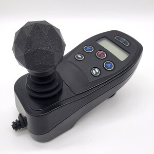 May include: A black joystick with a textured, black, spherical handle and a control panel with buttons and a digital display.
