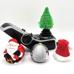 Könnte beinhalten: Ein schwarzer und silberner Joystick mit einem grünen Weihnachtsbaum oben drauf. Es gibt eine Weihnachtsmannfigur, einen silbernen Weihnachtsbaumschmuck mit Schneeflockenmuster und eine rote Weihnachtsmütze.