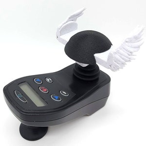 Könnte beinhalten: Ein schwarzer Joystick-Controller mit digitaler Anzeige und Tasten, gekrönt von einer schwarzen Kuppel und weißen Flügeln. Der Controller hat einen runden Sockel und ist vor weißem Hintergrund platziert.