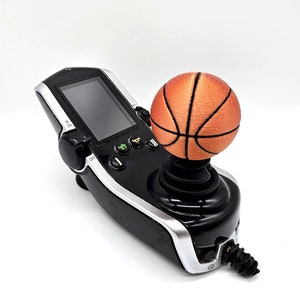 May include: A black joystick controller with a screen and buttons. The joystick is topped with an orange basketball.