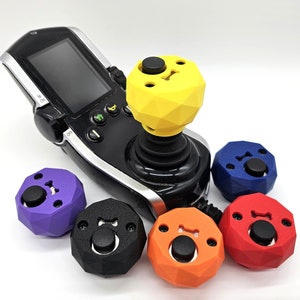 May include: A black joystick controller with a yellow, purple, blue, black, and orange button on top. The buttons have a bone-shaped design.