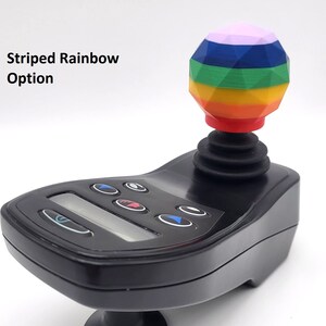 May include: A black joystick with a rainbow striped ball on top. The joystick has a digital display and several buttons.