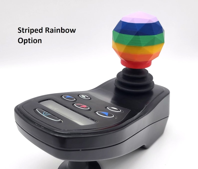 May include: A black joystick with a rainbow striped ball on top. The joystick has a digital display and several buttons.