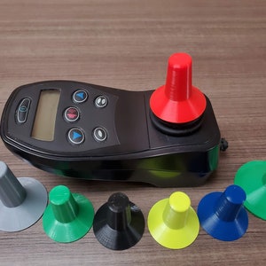 Peut inclure: Un contrôleur de joystick noir avec un dessus de joystick interchangeable rouge, vert, bleu, jaune, gris et noir. Le contrôleur de joystick possède un écran numérique et plusieurs boutons.