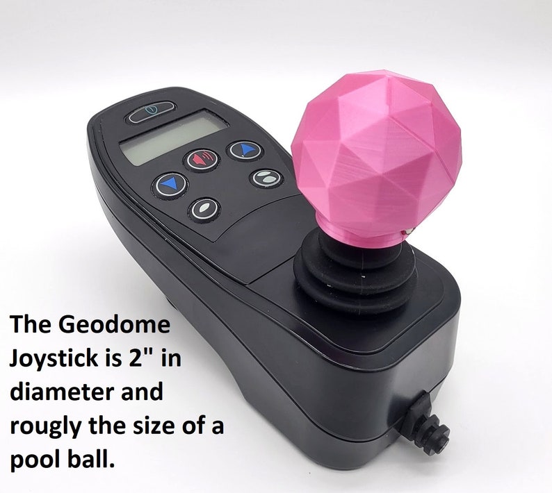 May include: A black joystick with a pink, geometric-shaped knob. The joystick is 2 inches in diameter and is roughly the size of a pool ball.