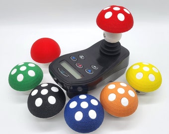 May include: A black joystick controller with six colourful mushroom-shaped buttons. The buttons are red, green, yellow, orange, black, and blue. Each button has white dots on top.