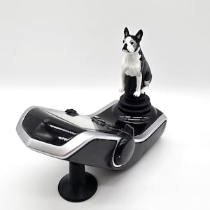 May include: A black and white Boston Terrier figurine sits atop a black joystick with a silver base. The joystick is designed for gaming and has a textured surface.