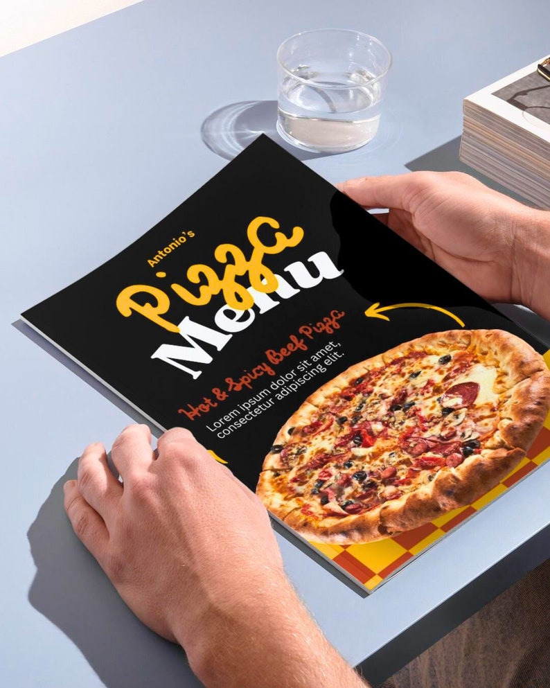 May include: A black and white menu with the text "Antonio's Pizza Menu" in yellow and red. The menu features a photo of a hot and spicy beef pizza with a red and white checkered background. The text "Hot & Spicy Beef Pizza" is in red and white. The text "Lorem ipsum dolor sit amet, consectetur adipiscing elit." is in white.