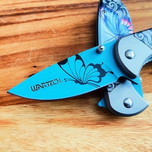 May include: A blue pocket knife with a butterfly design and the word "WARTECH" engraved on the blade.