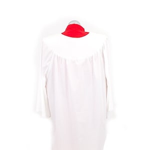 May include: A white robe with long sleeves and a red collar. The robe is worn over a red skirt.