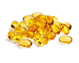 May include: A pile of yellow softgel capsules on a white background.