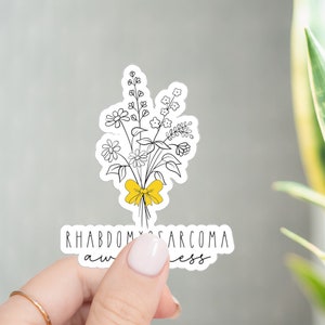 May include: A white sticker with a black line drawing of a bouquet of flowers tied with a yellow ribbon. The text "Rhabdomyosarcoma awareness" is written below the flowers.