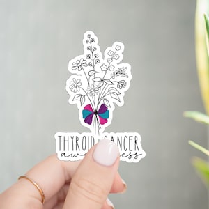 May include: A white sticker with a black outline of a bouquet of flowers tied with a pink, purple, and blue ribbon. The text "Thyroid Cancer Awareness" is below the flowers.
