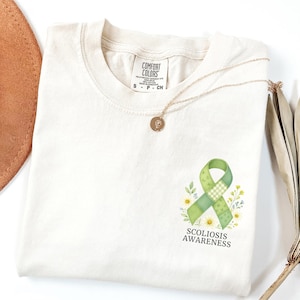 May include: A white ceramic mug with a black handle and the text "But First, Coffee" in a bold, black font. The mug is set against a neutral background, highlighting its simple design.