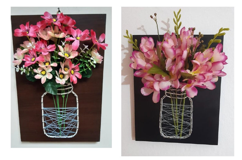 May include: Two framed string art pieces with pink flowers in a mason jar. The jars are made of string and the background is wood.