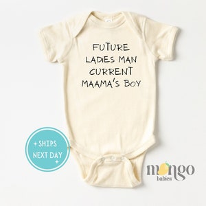 May include: A cream-colored baby onesie with black text that reads "FUTURE LADIES MAN CURRENT MAAMA'S BOY".