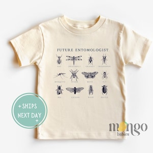 May include: A beige short-sleeved t-shirt with the text "FUTURE ENTOMOLOGIST" printed on the front. The shirt features a graphic of various insects, including an ant, dragonfly, cricket, treehopper, mosquito, spider, moth, fly, bee, cicada, wasp, and beetle.