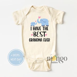 May include: A white baby onesie with short sleeves features a blue elephant and a smaller blue elephant with pink hearts above them. The text "I HAVE THE BEST GRANDMA EVER" is printed in black below the elephants.