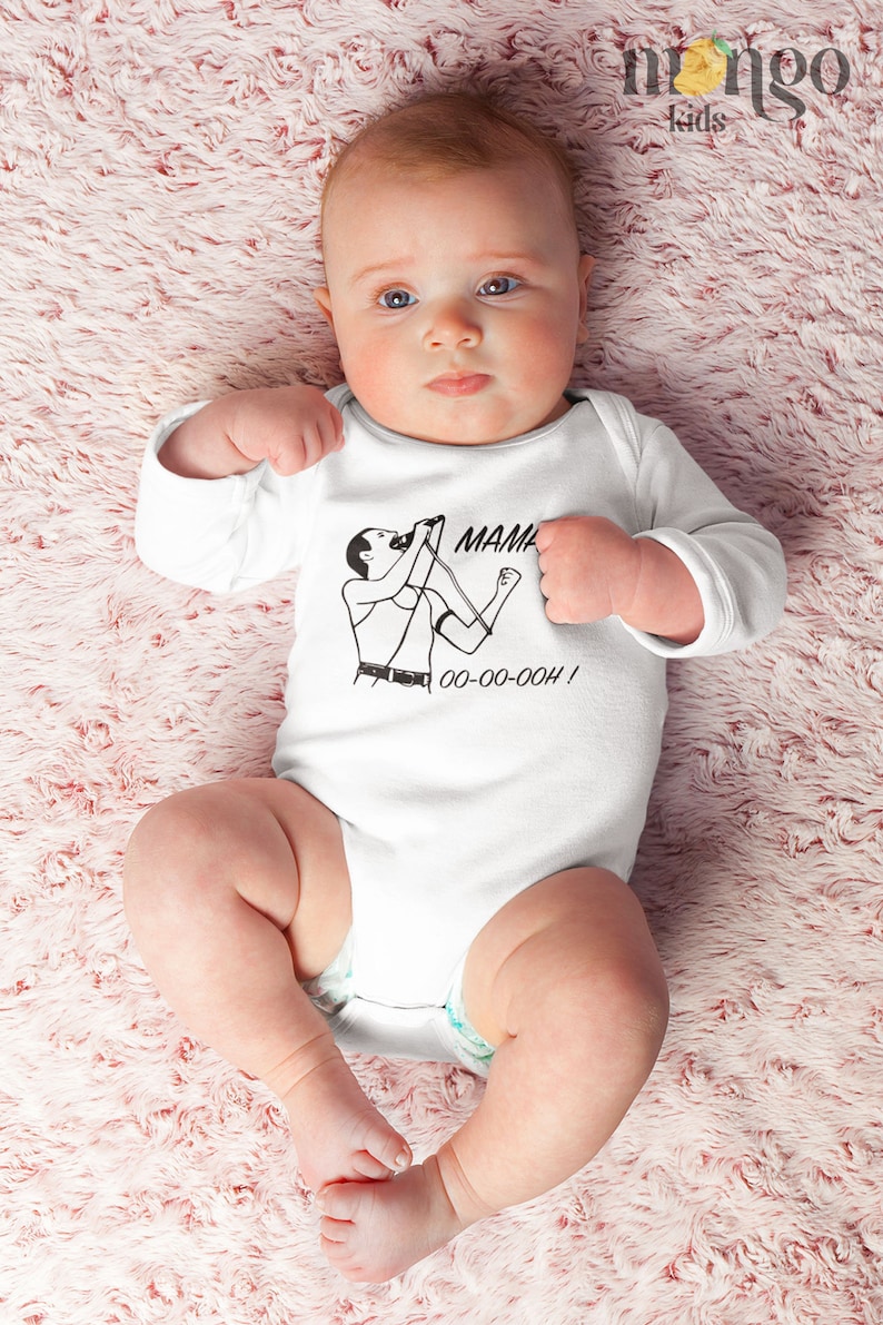 Może przedstawiać: Biały śpioszek z długimi rękawami z czarno-białą ilustracją osoby śpiewającej w mikrofon. Tekst "MAMA OO-OO-OOOH!" jest nadrukowany pod ilustracją.