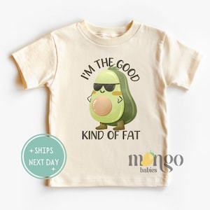 Peut inclure: Un t-shirt beige clair avec un avocat de dessin animé portant des lunettes de soleil et le texte "Je suis le bon genre de gras".
