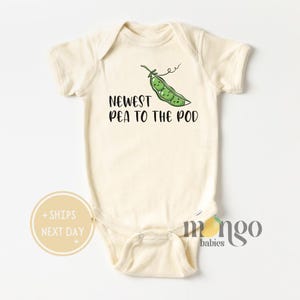May include: A cream-colored baby onesie with short sleeves features a green pea pod with four peas inside. The text "Newest Pea to the Pod" is printed in black below the pea pod.