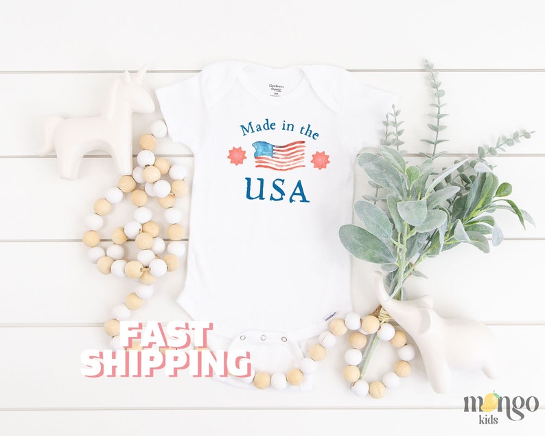 May include: White baby onesie with a red, white, and blue American flag and the text "Made in the USA".