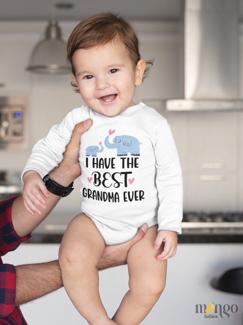 May include: A white long-sleeve baby onesie with a graphic of two blue elephants and the text "I have the best grandma ever" in black with pink hearts.