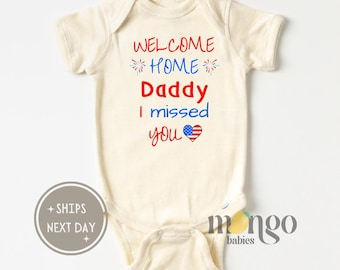 Puede incluir: Un body blanco para bebé con el texto "Welcome Home Daddy I missed you" en rojo y azul. El texto está decorado con fuegos artificiales y un corazón con la bandera estadounidense.