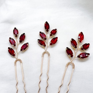 May include: Three gold hair pins with red crystal leaves. Each pin has a delicate, twisted wire design and features multiple red crystal leaves.