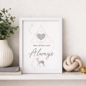 May include: A framed print with a white border features a gray geometric heart design, a deer silhouette, and the word "Always" in cursive. The text "After all this time?" is above the word "Always". The print is displayed on a white shelf.