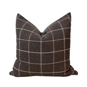 Op de afbeelding: Een bruin en wit geruit kussen met een vierkant patroon.