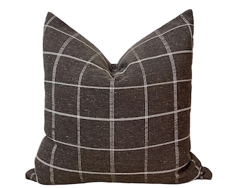 May include: A brown and white plaid throw pillow with a square pattern.