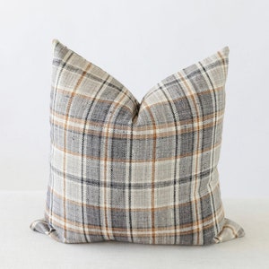 May include: A gray, beige, and brown plaid throw pillow with a square shape.
