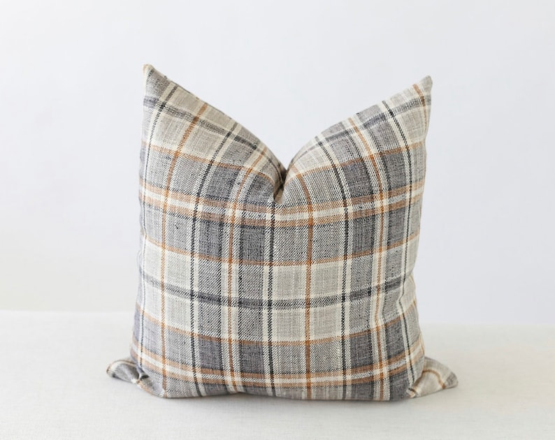 May include: A gray, beige, and brown plaid throw pillow with a square shape.