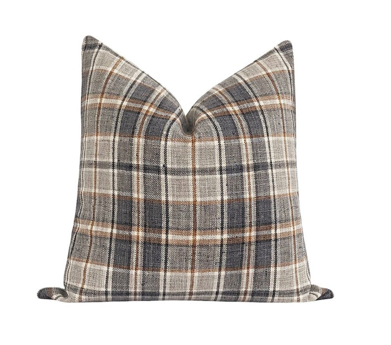 May include: A gray, brown, and white plaid throw pillow with a square shape.