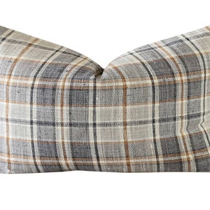 May include: A decorative throw pillow with a plaid pattern in shades of brown, gray, and white.