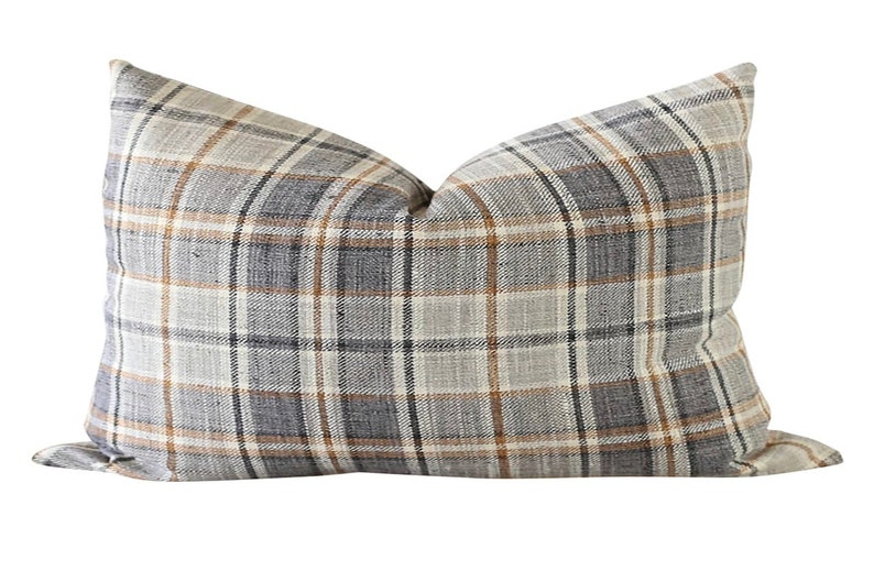 May include: A decorative throw pillow with a plaid pattern in shades of brown, gray, and white.