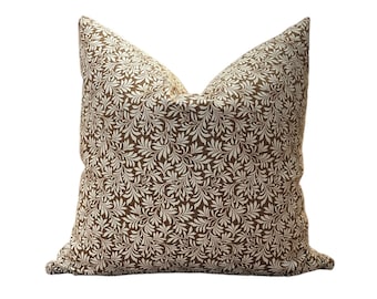 May include: A brown and white patterned pillow with a leafy design. The pillow is made of a soft, comfortable fabric and has a square shape.