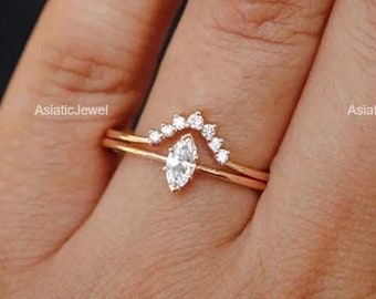 Può includere: Un delicato anello d'oro con un diamante a forma di marquise e una fila di diamanti più piccoli a forma di arco.