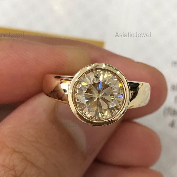 Anillo de compromiso de oro amarillo de 14 quilates con bisel completo de moissanita de corte redondo.