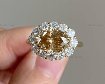 May include: A gold ring featuring a large, marquise-cut, cognac-colored center stone surrounded by a halo of small, round, brilliant-cut white diamonds. The setting is crafted from polished yellow gold, highlighting the contrast between the warm brown central gemstone and the sparkling white accent stones.